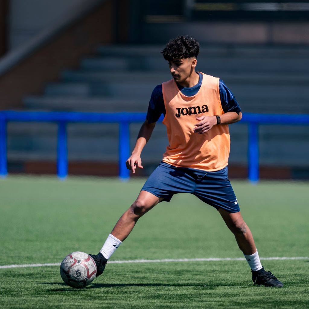 NXT footballer with football on pitch