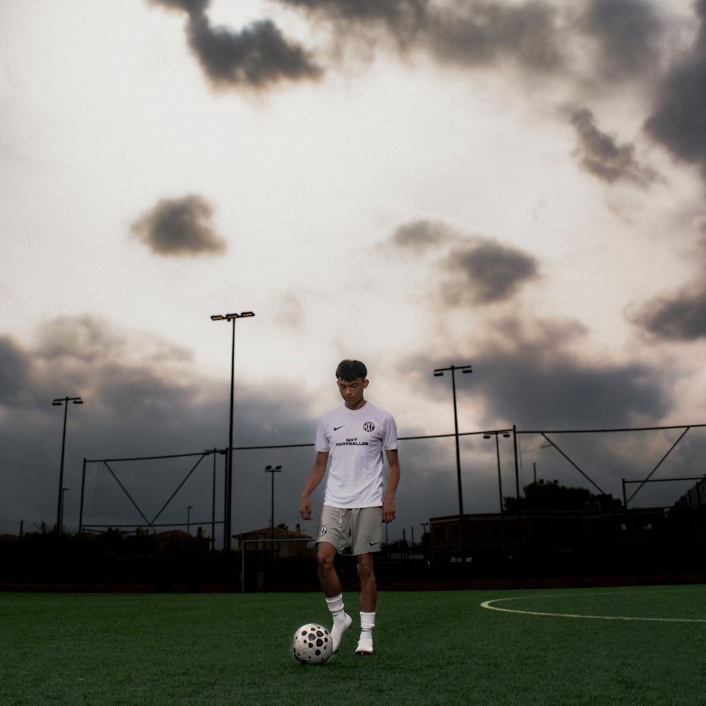 NXT footballer standing with football on pitch